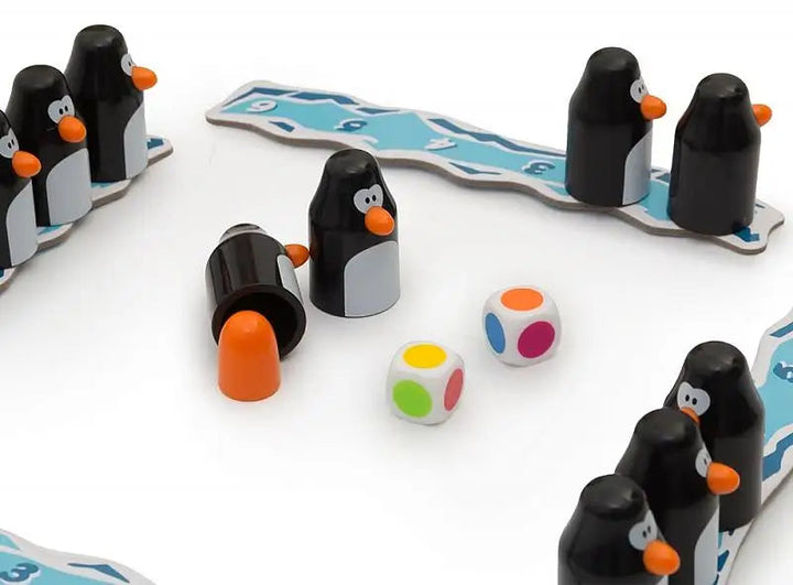 Close-up of a penguin piece beside a revealed orange egg and two color-dot dice