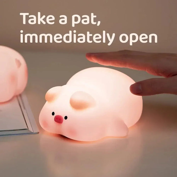Hand tapping a glowing pig-shaped silicone night light