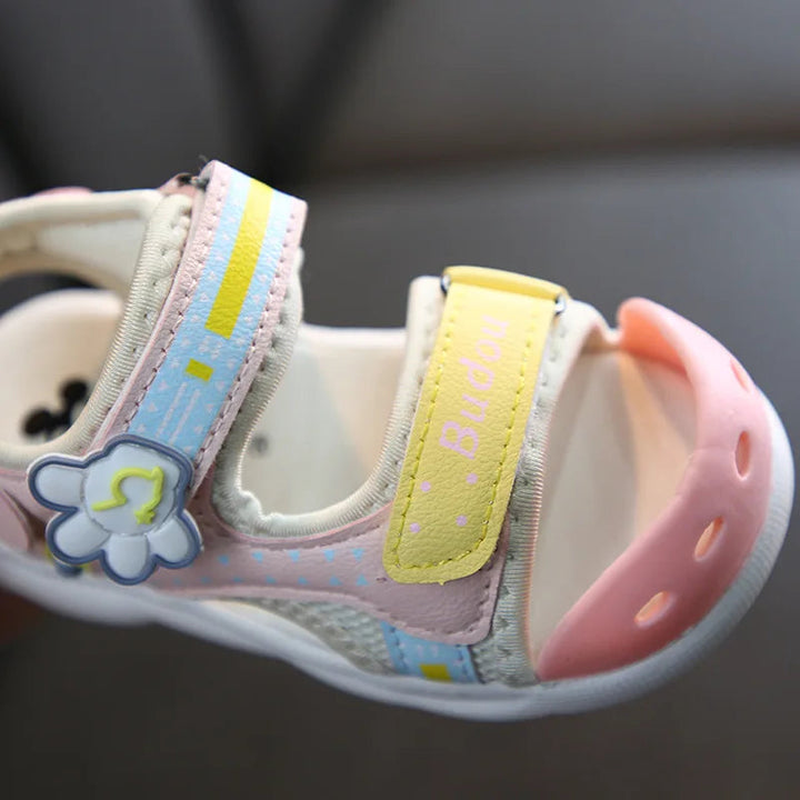 Close-up of a Pink A sandal with adjustable straps, a flower detail, and a rounded toe cap