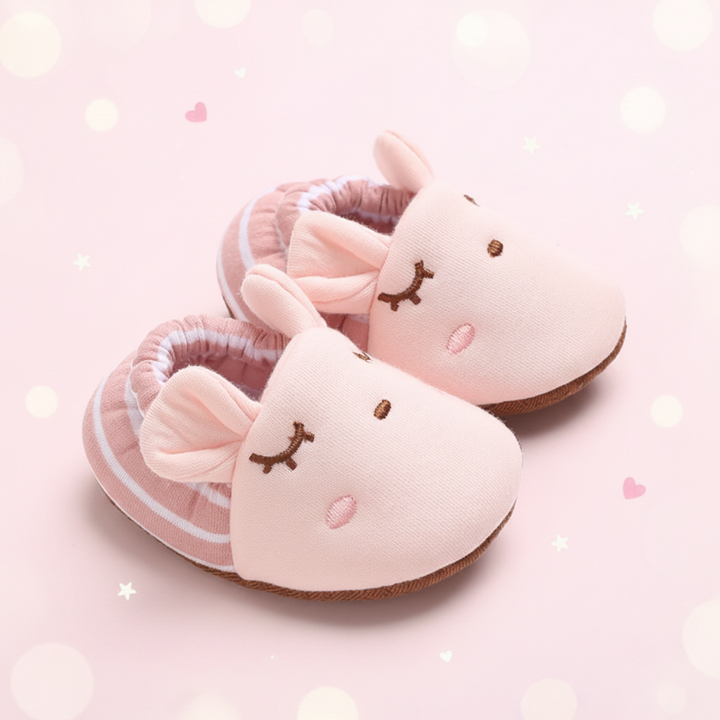 Pink baby shoes with animal ears, closed-eye embroidery and striped cuffs.