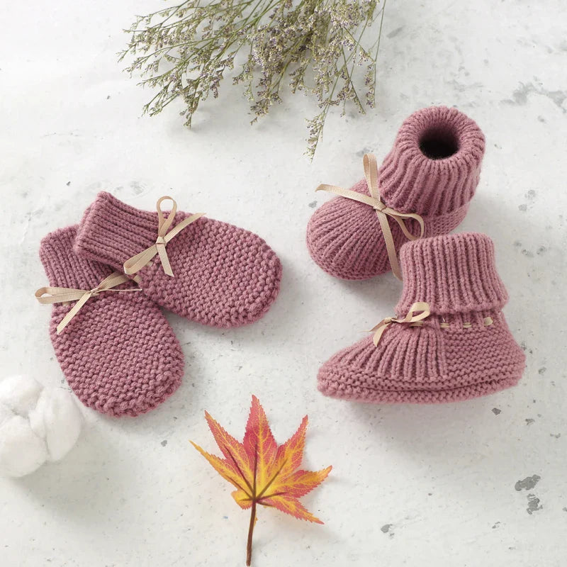 Pink knitted baby booties and matching mittens with beige ribbon bows