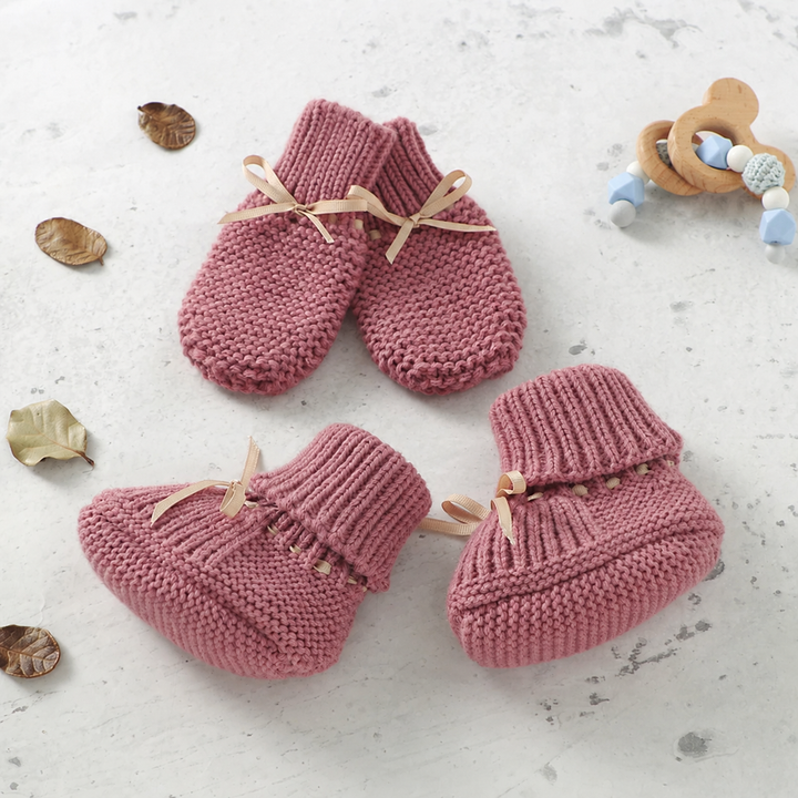 Pink knitted baby booties and matching mittens with ribbed cuffs