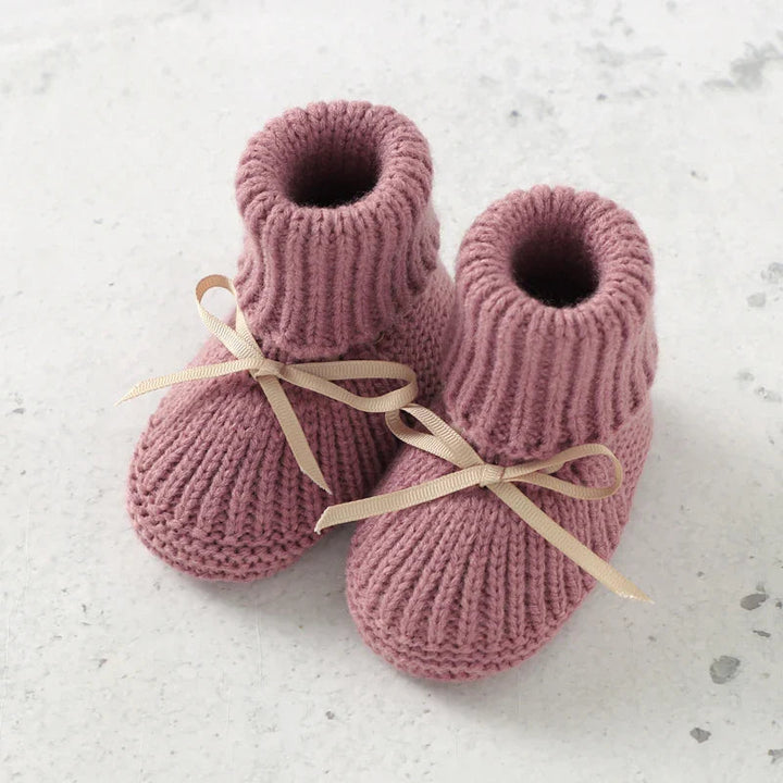 Pair of pink knitted baby booties with tall ribbed cuffs and ribbon bows