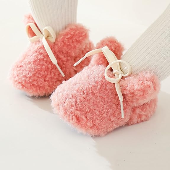 Pink bunny slippers with cream bows worn over white ribbed socks
