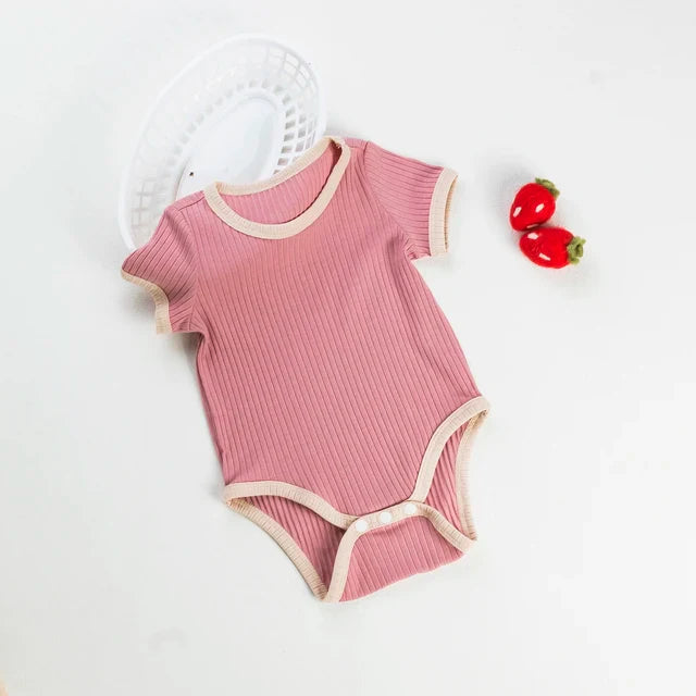 Pink ribbed baby romper with short sleeves, cream trim, and bottom snaps