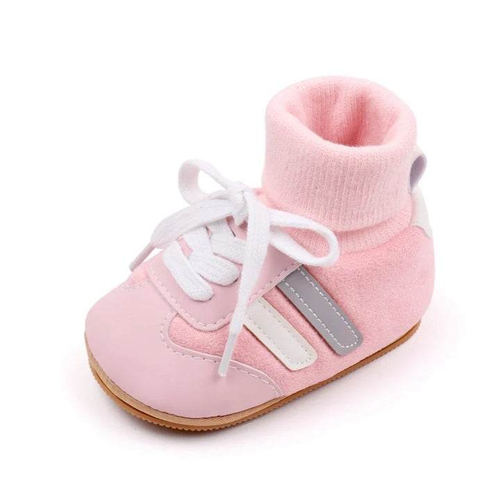 Pink baby shoe with a ribbed ankle cuff, white laces, and gray and white side stripes