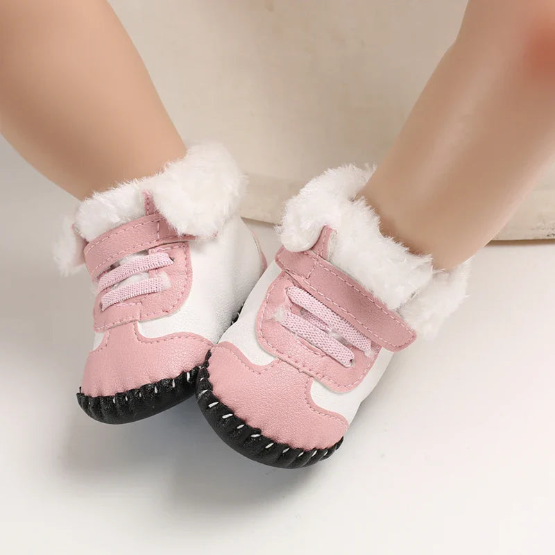 Pink and white baby winter boots worn on little feet, with fluffy cuffs and strap closures