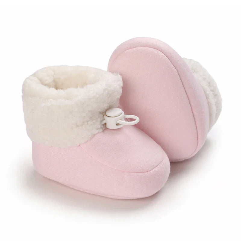 Pink baby winter boots with fluffy white cuffs, one turned to show the sole