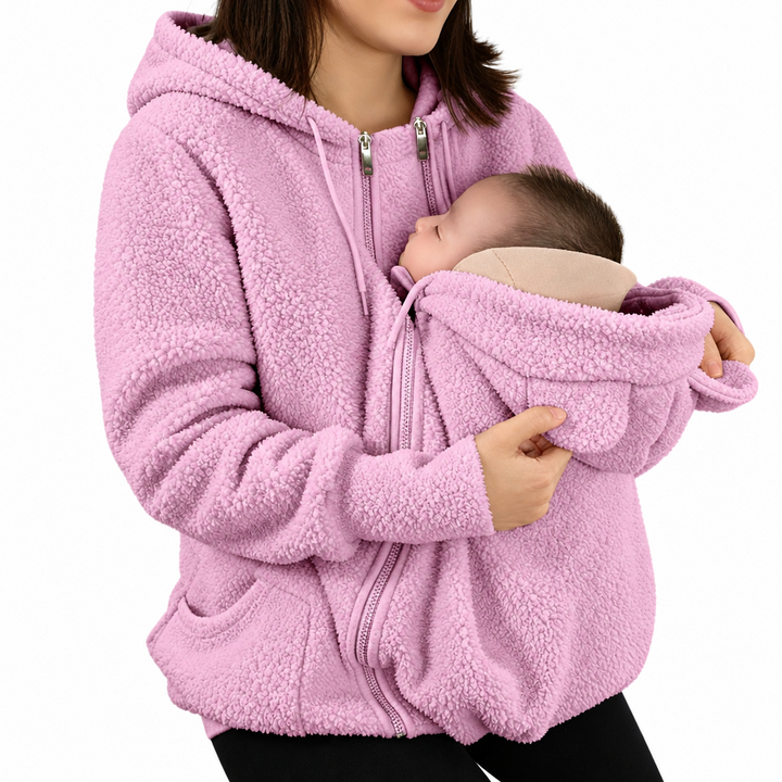 Pink babywearing jacket with side pockets shown on a woman holding a baby
