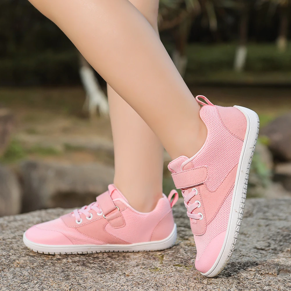 Child wearing pink barefoot sneakers with white soles on a stone ledge