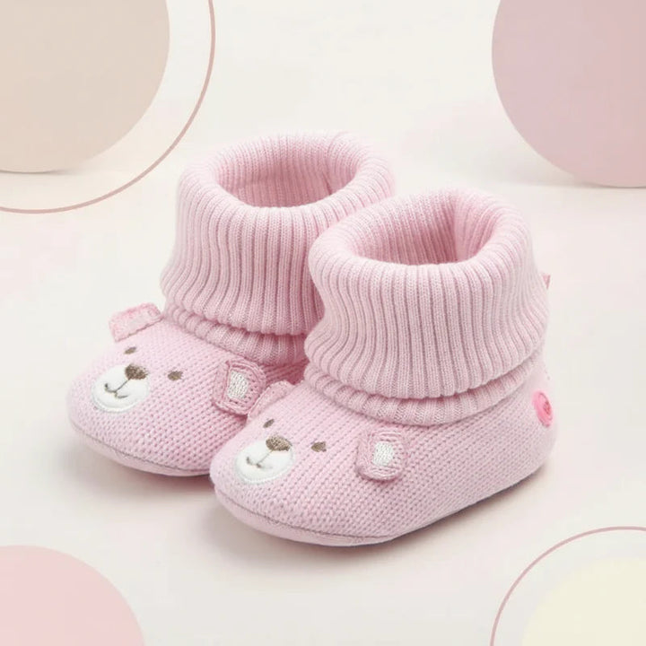 Pair of pink knit baby booties with bear faces and folded ribbed cuffs.
