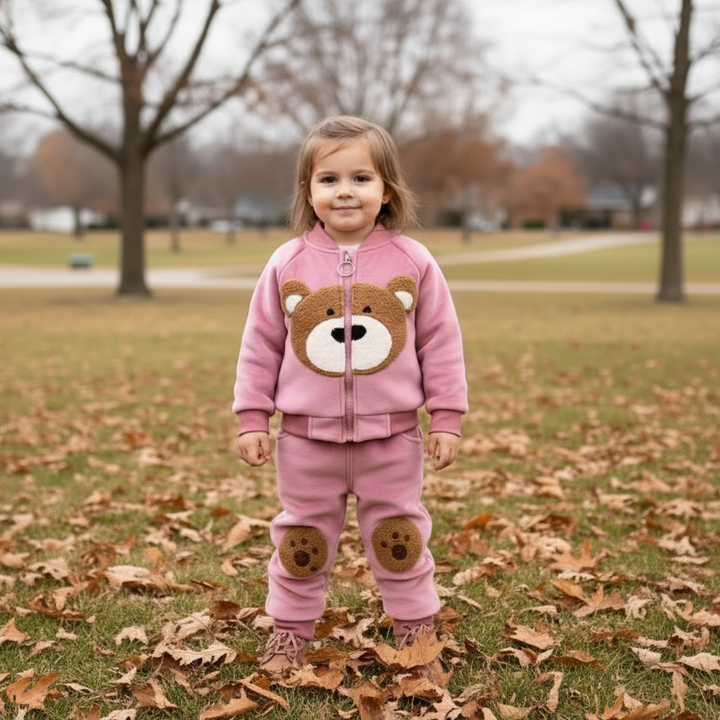 Child outdoors in a pink bear-face zip top and matching pants with paw details