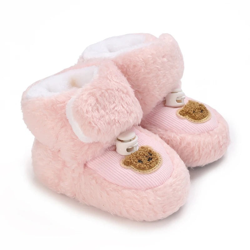 Pink plush baby shoes with bear patches and soft white lining.