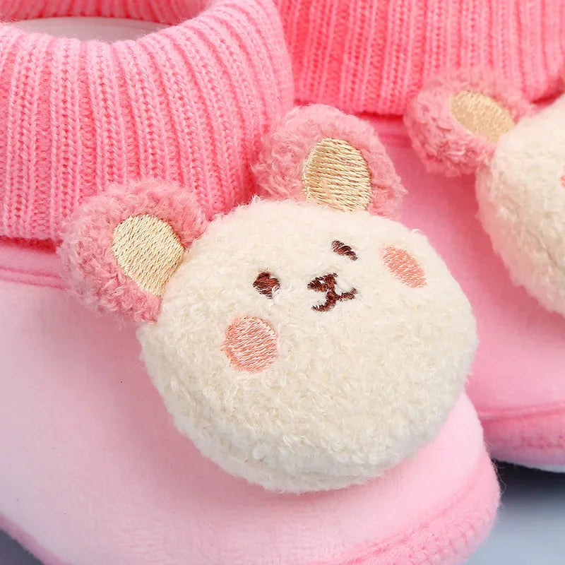Close-up of a plush bear face and knitted collar on pink baby slippers