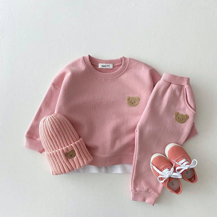 Pink bear-patch sweatshirt and pants styled with a matching knit hat and pink shoes