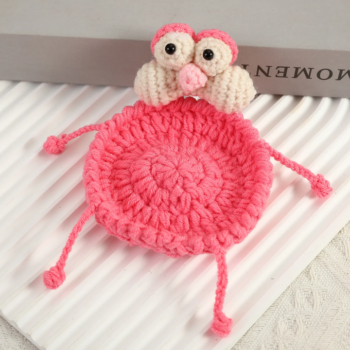 Pink bird design coaster with a cream face, large eyes, and slender crocheted legs