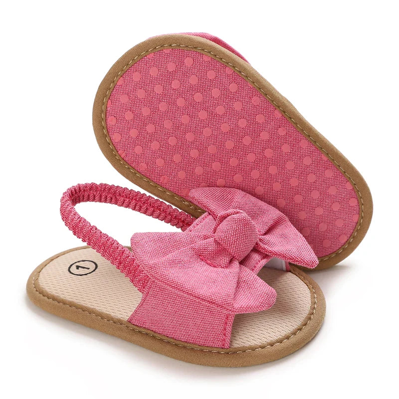 Pink bow baby sandals with one dotted sole facing up