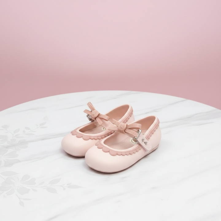 Pink Mary Jane shoes with matching bows and scalloped trim on a floral tablecloth