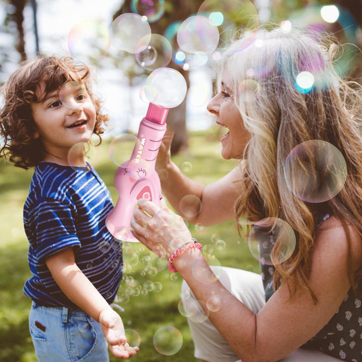 Adult and child watching bubbles from a pink electric bubble maker outdoors