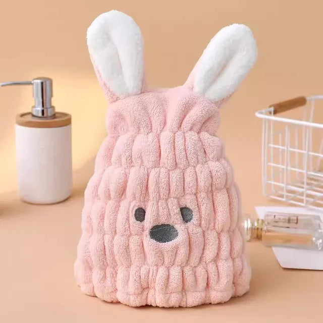 Pink bunny hair-drying cap showing its textured fabric, white ears, and stitched face