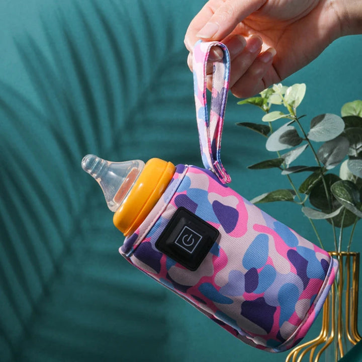 Hand carrying a pink camouflage bottle warmer by its fabric loop.