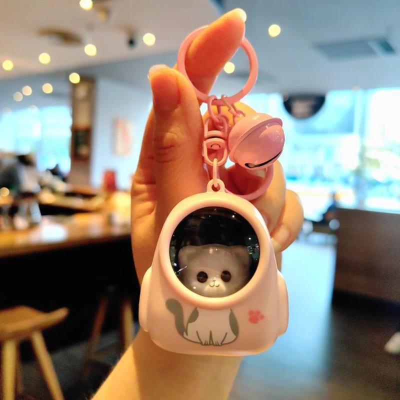 Pink capsule-style astronaut charm with an animal face, matching key ring, and bell