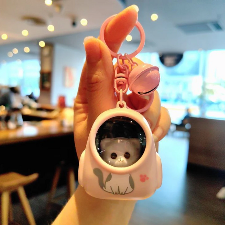 Pink capsule-style astronaut charm with an animal face, matching key ring, and bell