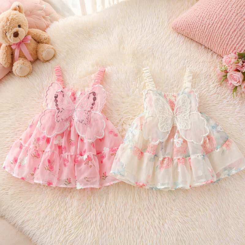 Pink and cream floral baby dresses with butterfly wings, laid flat side by side