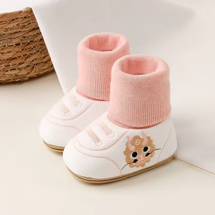 Pair of white baby shoes with pink knit cuffs and animal side motifs.