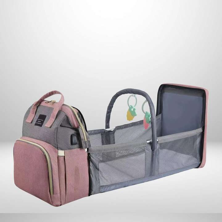 Pink and gray diaper bag with the daybed unfolded, mesh sides, and an overhead toy arch.