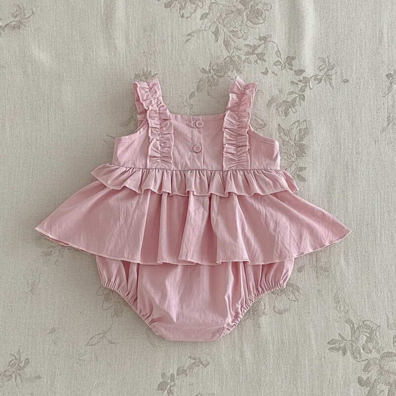 Pink baby dress romper showing bodice buttons, ruffled straps and a gathered skirt
