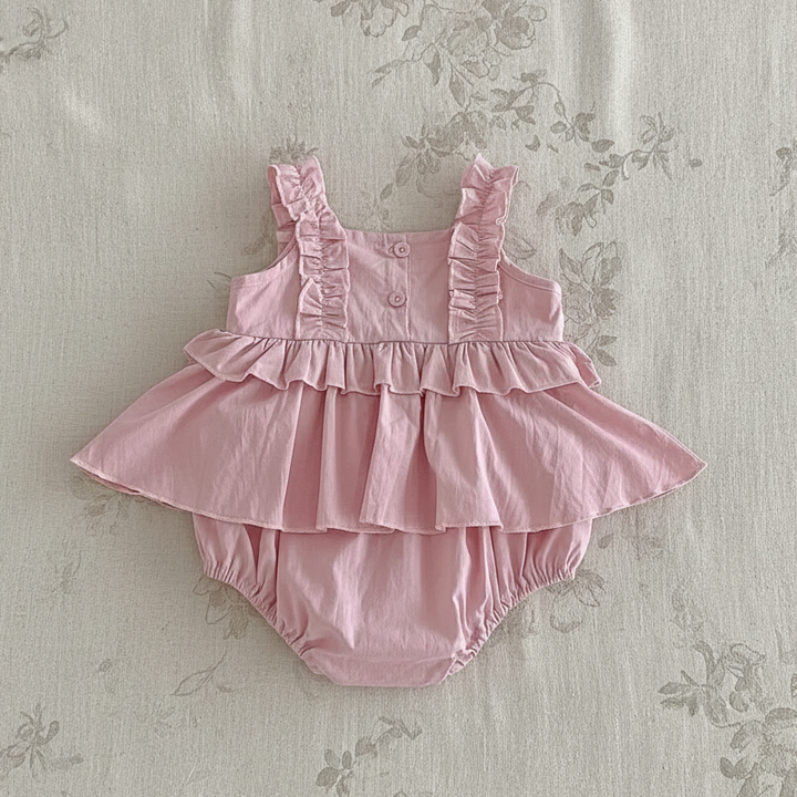 Pink baby dress romper showing bodice buttons, ruffled straps and a gathered skirt