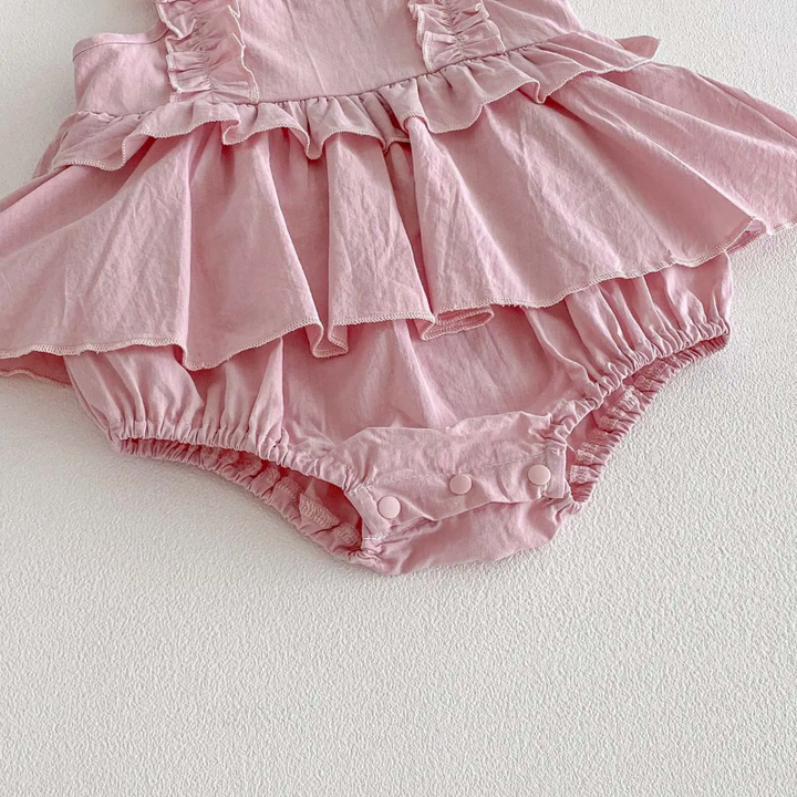Pink baby dress romper with the snap tab open beside its elastic leg opening