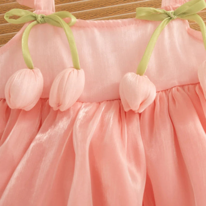 Pink tulip appliques and green ribbon bows across the dress bodice