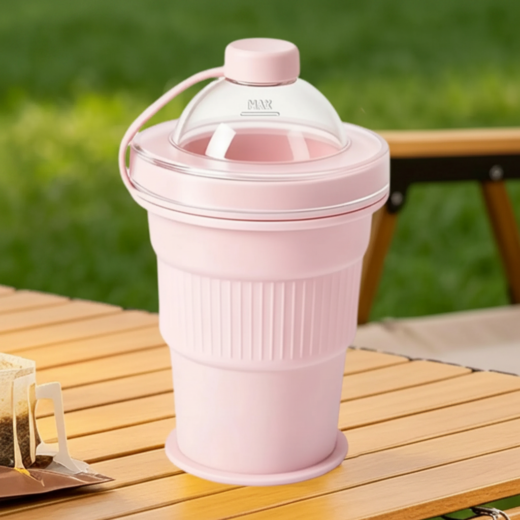 Pink silicone drinking cup with a clear domed lid and tethered cap on an outdoor table