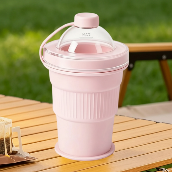 Pink silicone drinking cup with a clear domed lid and tethered cap on an outdoor table