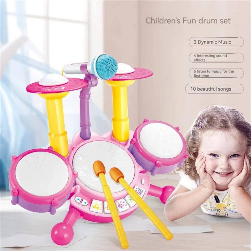 Pink toy drum set with a microphone and two drumsticks displayed beside a smiling child