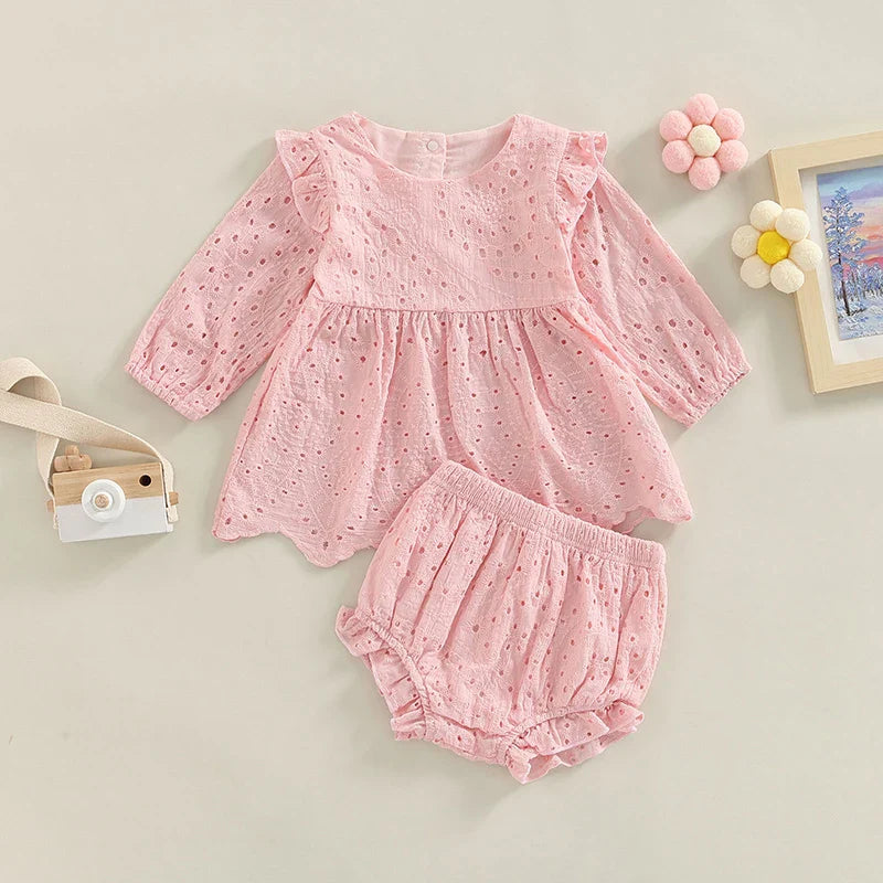 Pink eyelet baby top with ruffled shoulders and matching shorts arranged below.