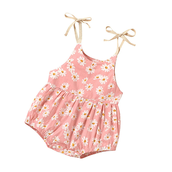 Angled view of a pink floral baby romper with tie shoulders and gathered leg openings
