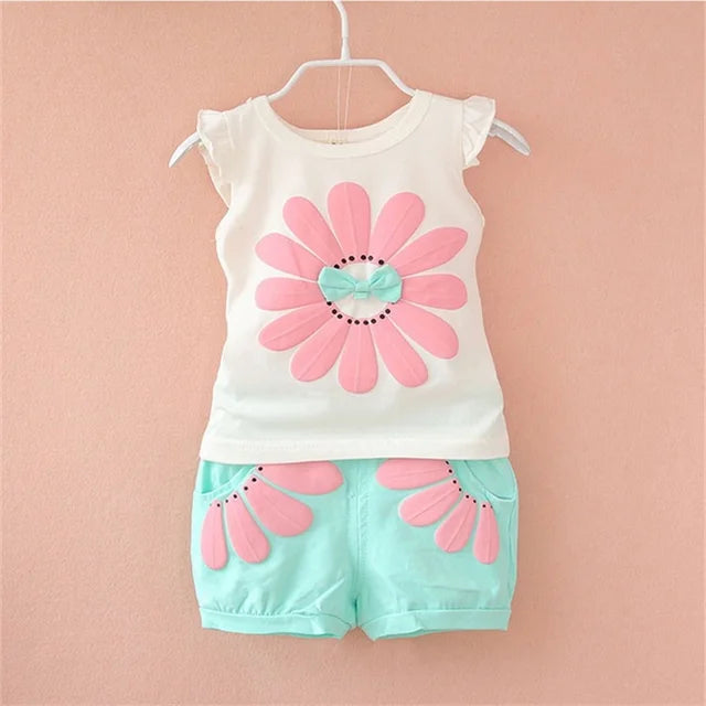 Pink-flower white baby top and aqua floral shorts displayed together on a hanger