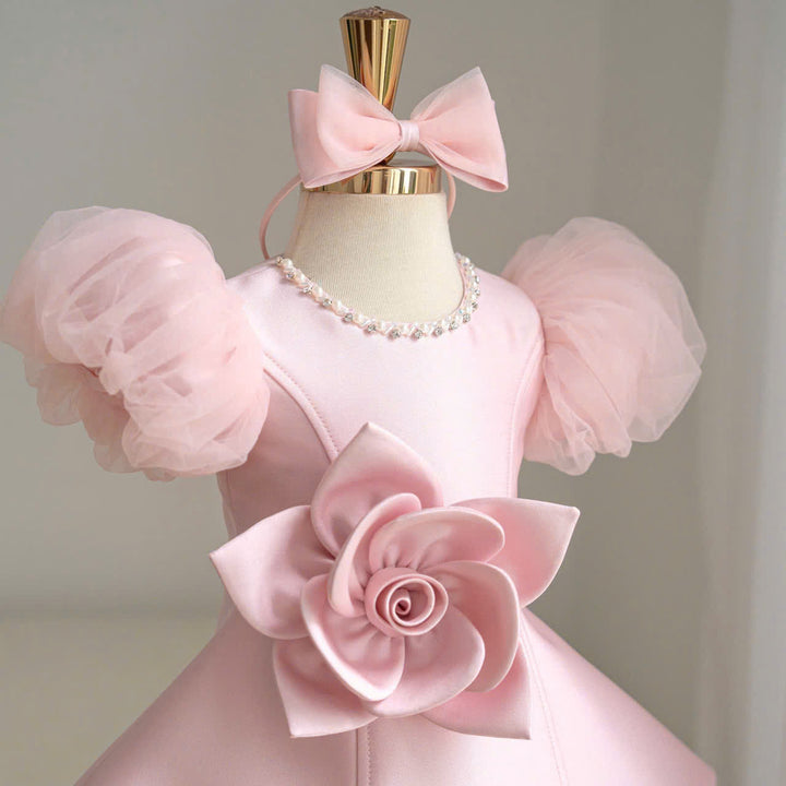 Pink dress close-up with layered puff sleeves, neckline trim and a large pink flower