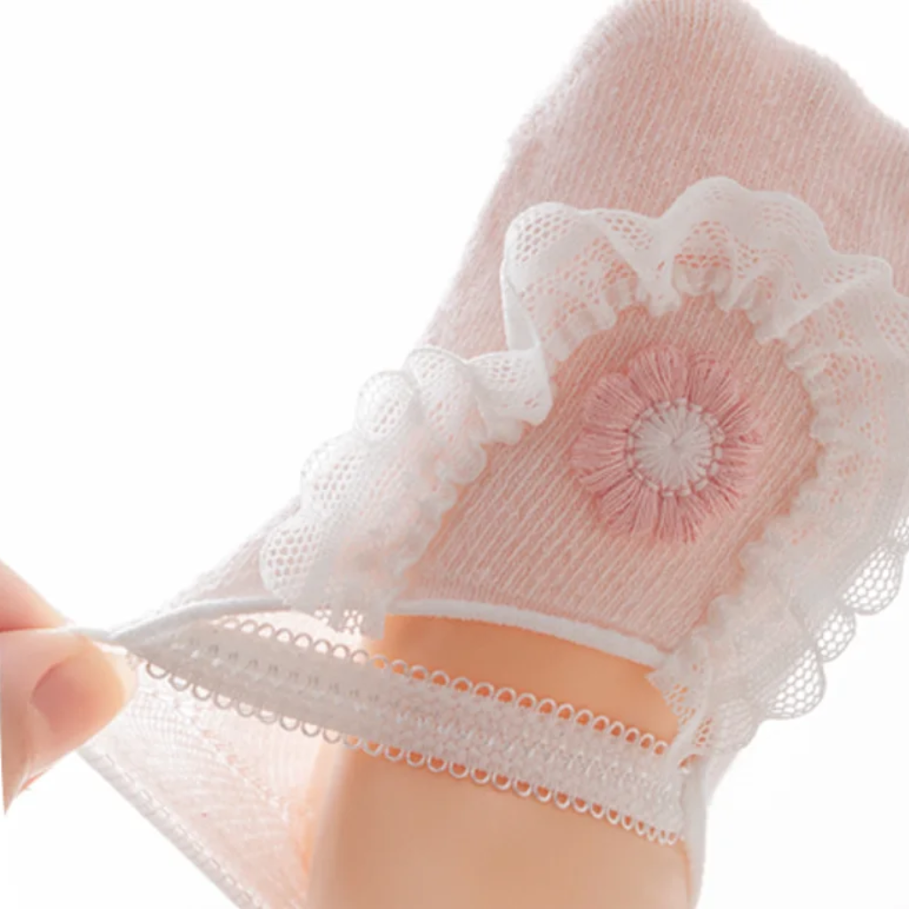 Close-up of a hand stretching the band on a pink flower baby sock