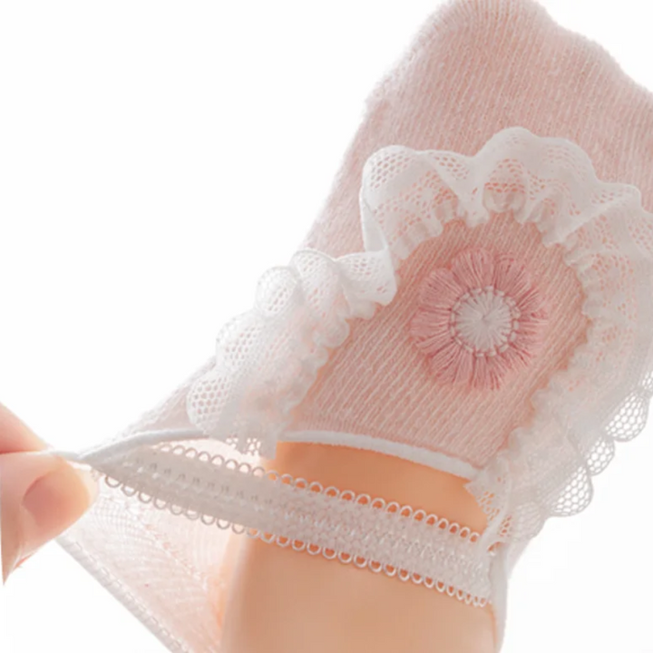 Close-up of a hand stretching the band on a pink flower baby sock