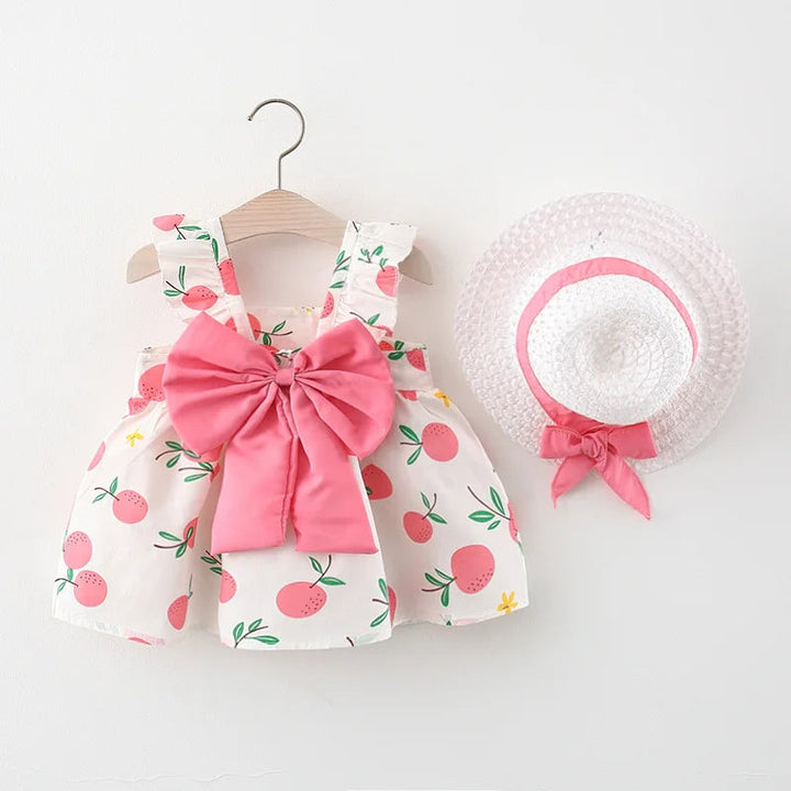 Pink fruit-print dress with an oversized pink bow and coordinating straw hat