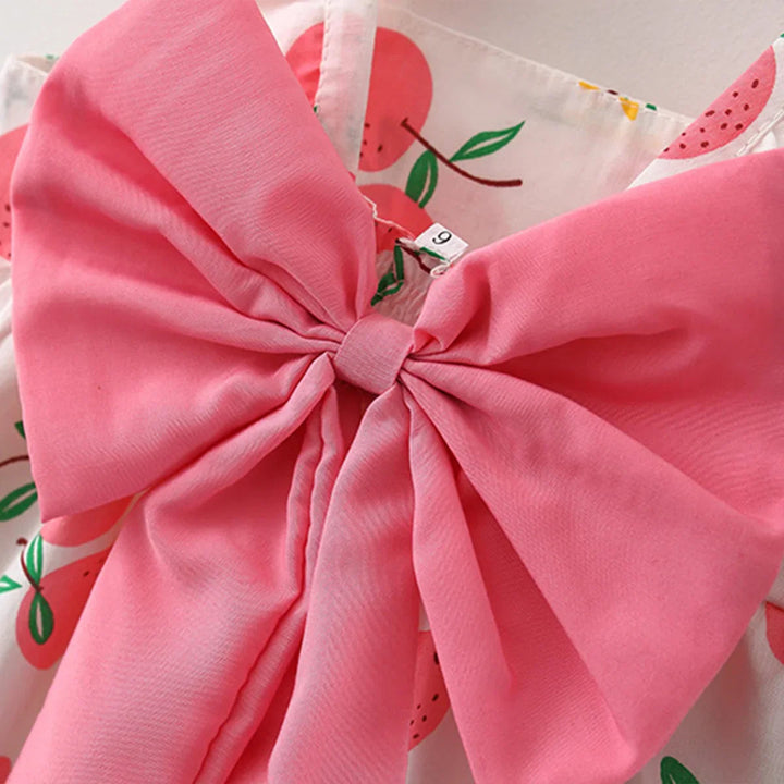 Close-up of the oversized pink bow on the fruit-print dress