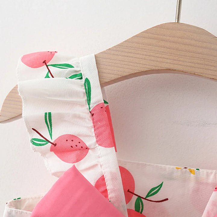 Close-up of a ruffled shoulder strap on the pink fruit-print dress