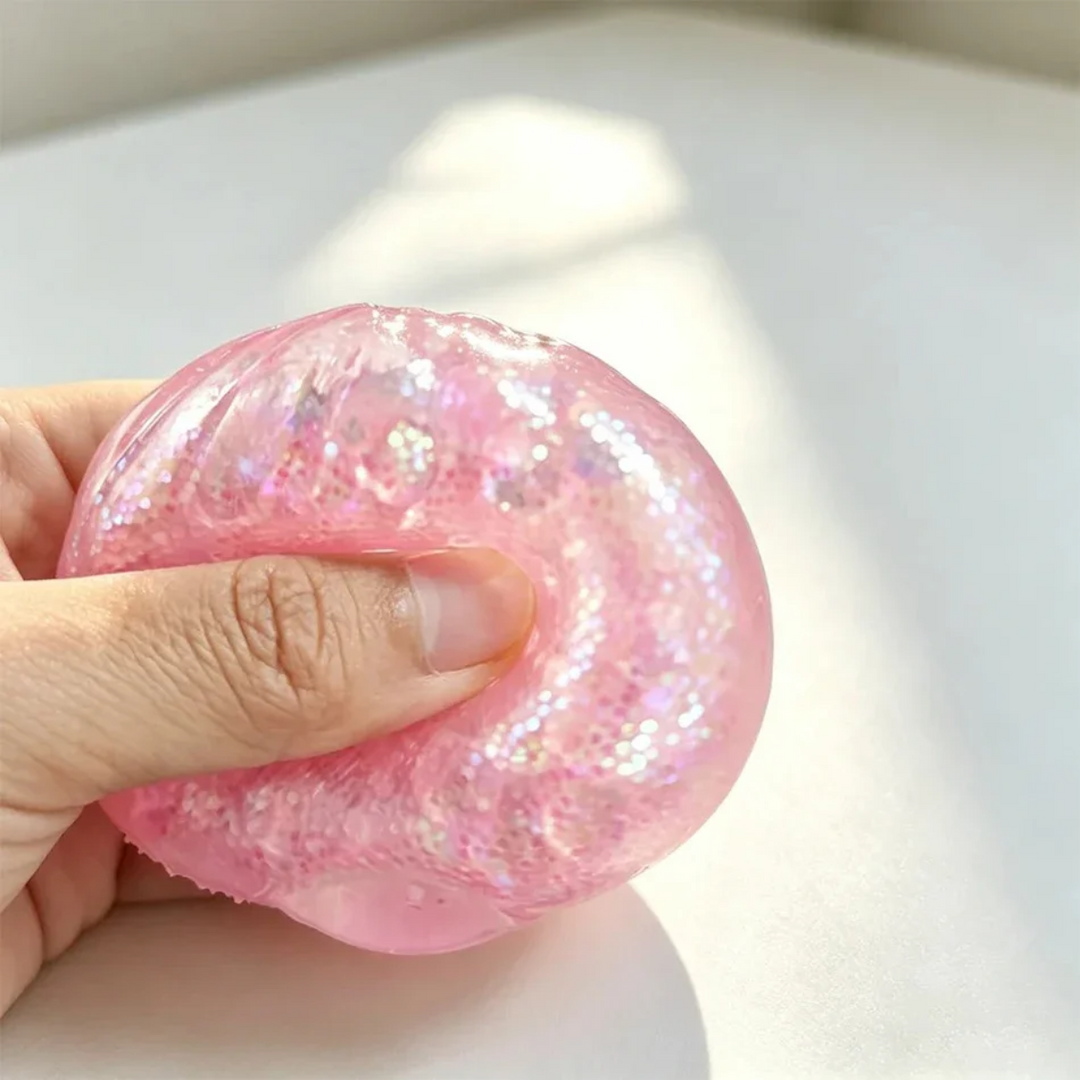 Close-up of a thumb pressing into a pink glitter dumpling squishy