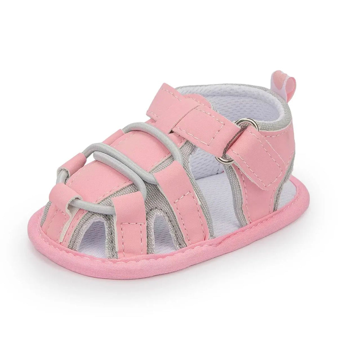 Pink baby sandal with gray trim, front cords and an ankle strap