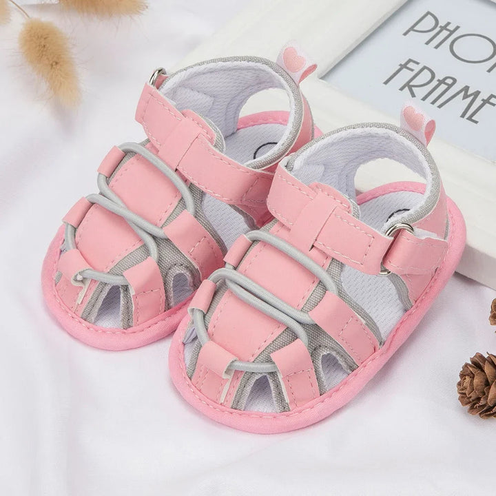 Pink and gray baby sandals with ankle straps and crisscross front cords