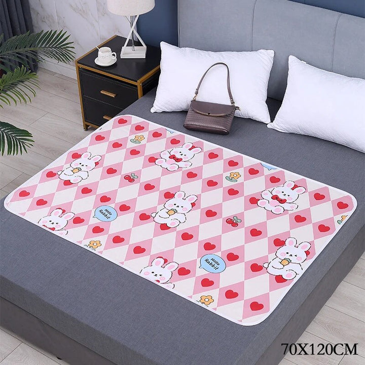 Pink heart-and-bunny changing mat on a gray bed, labeled 70 x 120 cm.